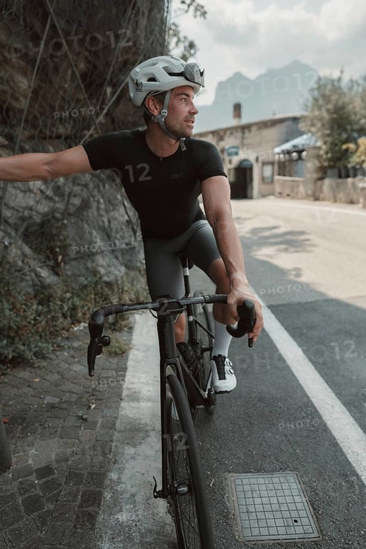 Young man riding a racing bike on Lake Garda. Sunny weather and dolce vita
