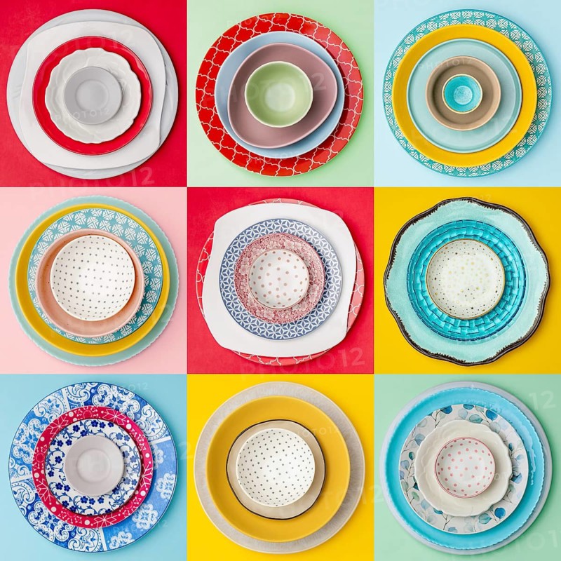 A colorful, overhead view of nine diverse plate arrangements. Each set features unique patterns and colors, creating a vibrant and artistic display on a pastel background