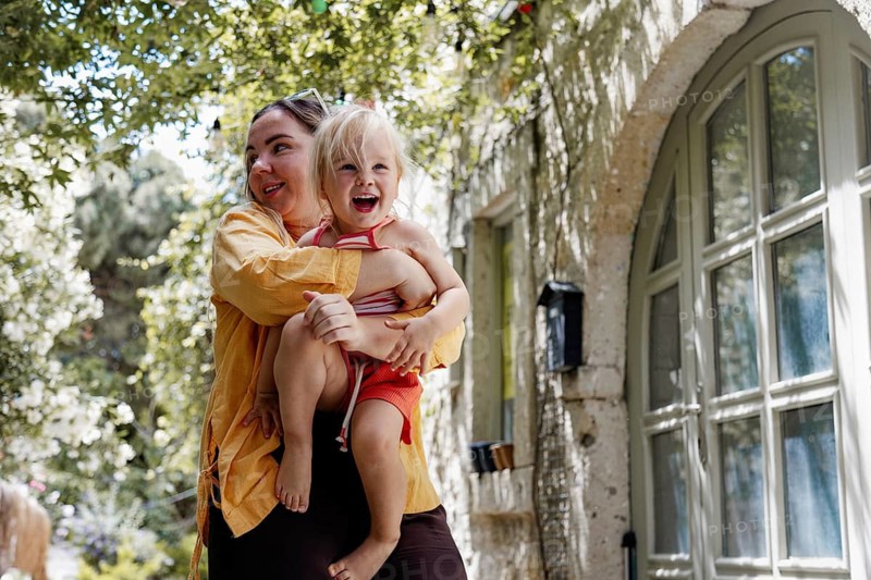 A joyful mother holding her cheerful daughter as they enjoy a sunny day outside. The scene captures a heartwarming moment of bonding and happiness in a serene outdoor setting