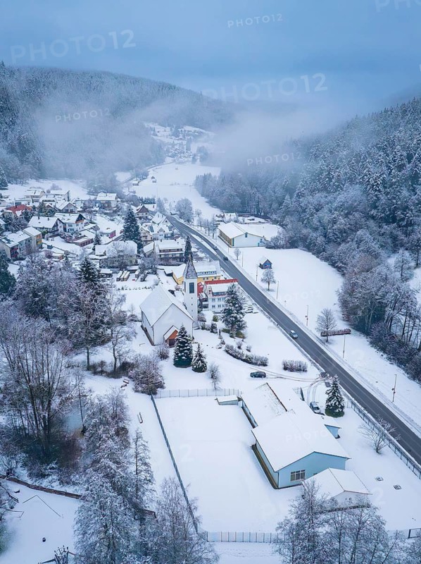 A village with a church and streets, surrounded by a snowy landscape and forests, Enzklösterle, Calw district, Black Forest, Germany