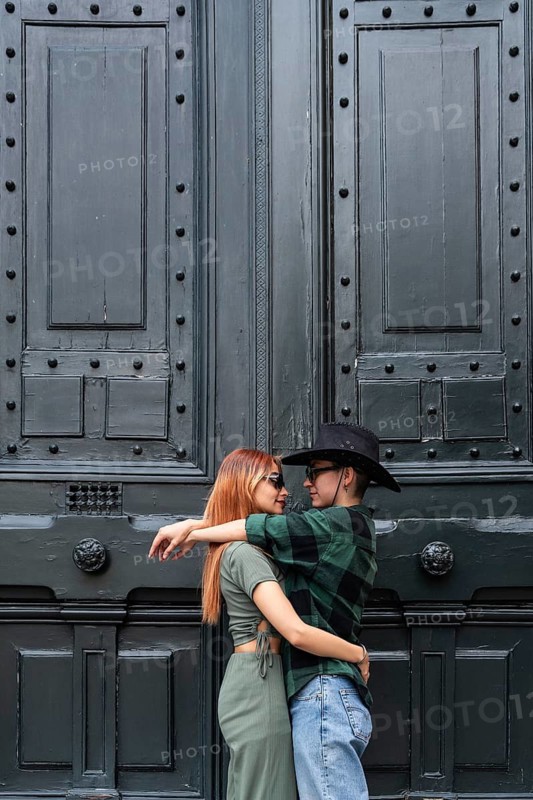 A Colombian lesbian couple shares an intimate embrace in front of a rustic door, celebrating love and diversity. This image embodies LGBTQIA+ pride and inclusivity