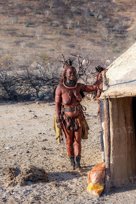 Married Himba woman leaning against a traditional mud house, traditional Himba village, Kaokoveld, Kunene, Namibia