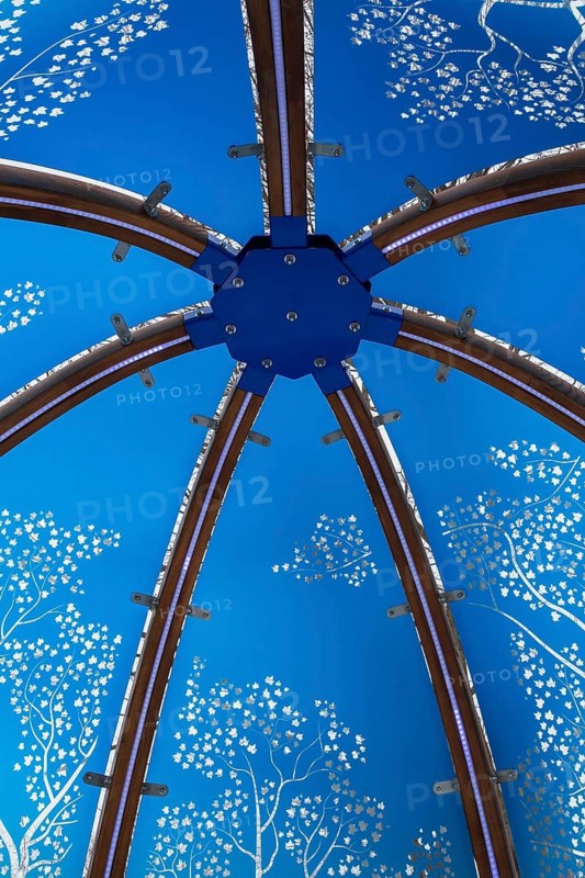 Close-up of backlit blue tinted plexiglass and curved wood panels canopy decorated with white maple leaves in the wind theme motifs inside interactive cocoon rocking chair made by Olivier Landreville, Horizon Art Installation, Ile des Moulins, Old Terrebonne, Quebec, Canada