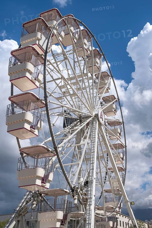 A large Ferris wheel with numerous cabins in front of a partly cloudy blue sky, Tirana, Albania