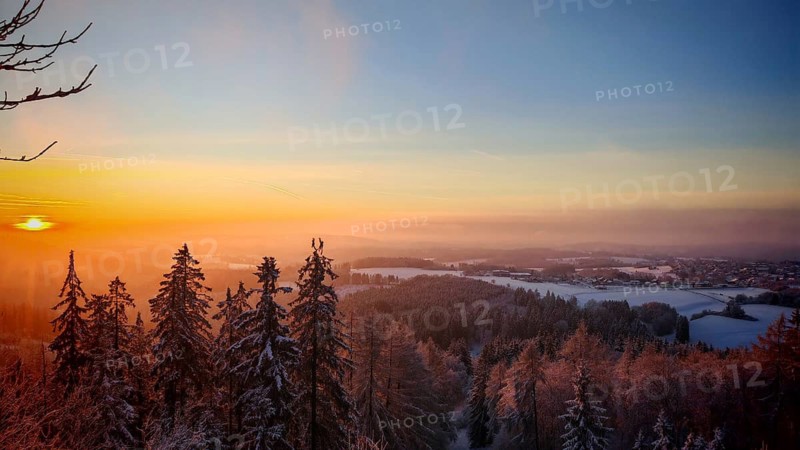 View from Döbra Berg, wide winter landscape with spectacular orange sunset with snow and trees, Franconian Forest nature park Park