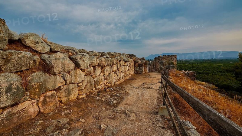 Cyclopean wall, wall of stones along a path on a hill with cloudy sky, Tiryns, ancient city in Argolis, Mycenaean, Peloponnese, Greece