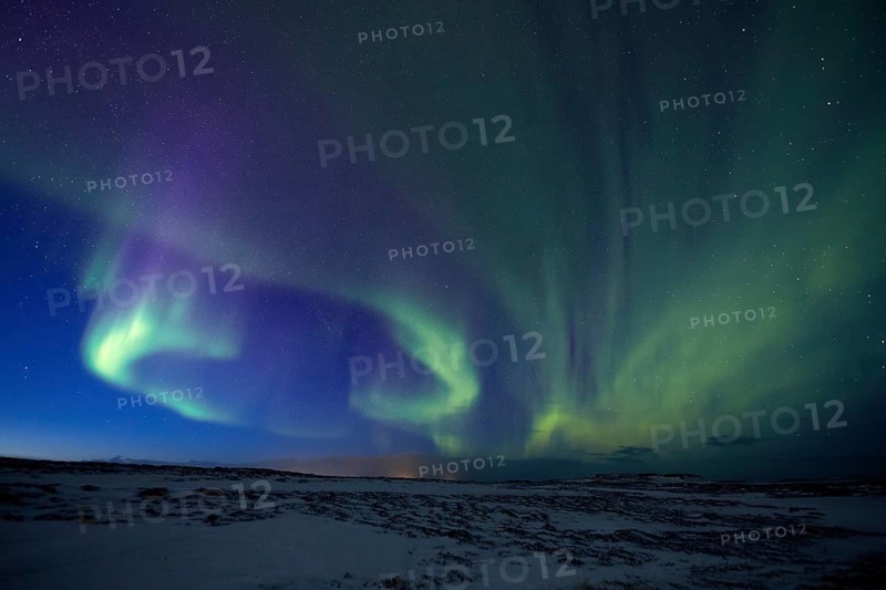 Aurora borealis in green colors over snow covered landscape at night, Lapland, Finland