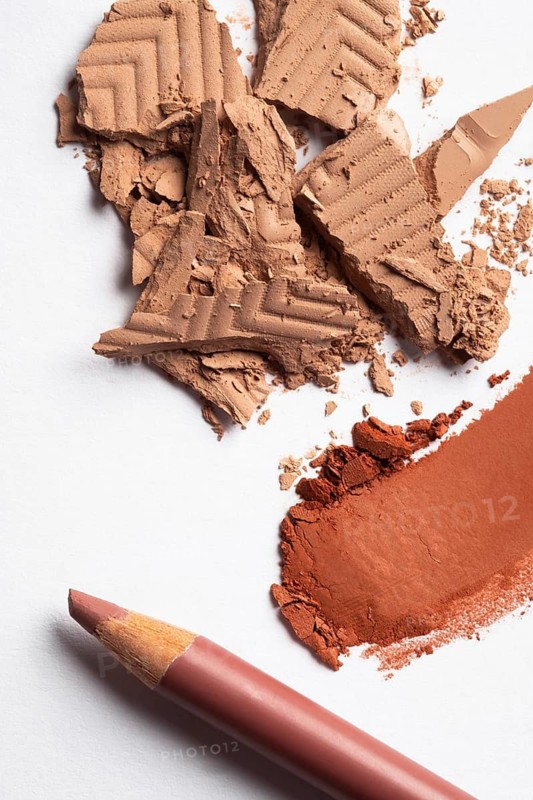 A vivid display of crushed eye shadow and makeup powder showcasing texture and color contrasts. Highlighting makeup artistry with a red pencil, perfect for creative beauty designs