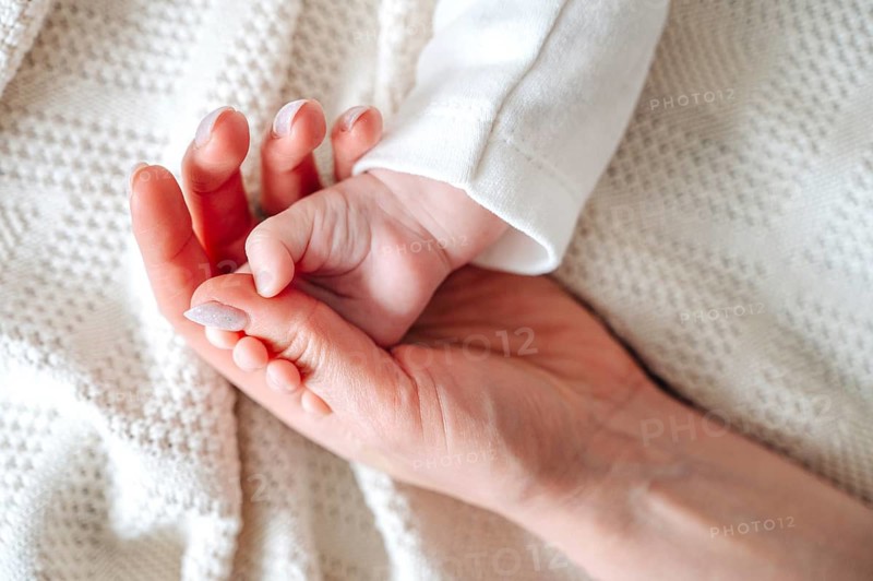 A tender moment as a mother gently holds her newborn baby's tiny hand. The warm scene speaks of love, care, and the deep connection between father and daughter