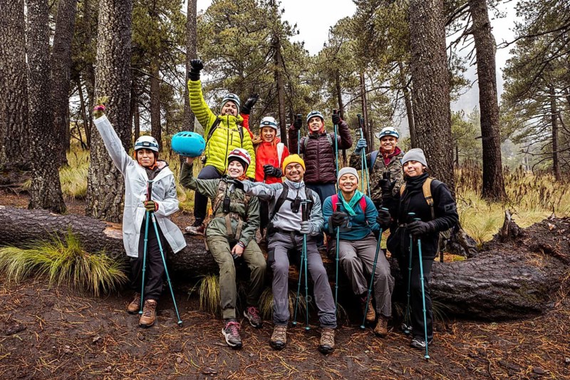 A group of enthusiastic hikers enjoy a rainy day on a scenic forest trail, surrounded by tall trees and lush greenery, capturing the essence of outdoor adventure and camaraderie