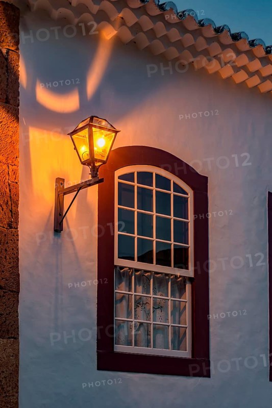 Window and facade of an old colonial-style house illuminated by a lantern at night in Tiradentes, Minas Gerais, Brasil