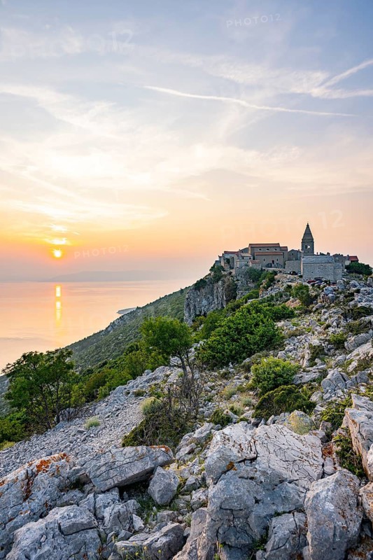 Small fishing village (Lubenice) built on the rocks high above the sea with a view of the sea on a sunny day at sunset on the island of Cres, Croatia