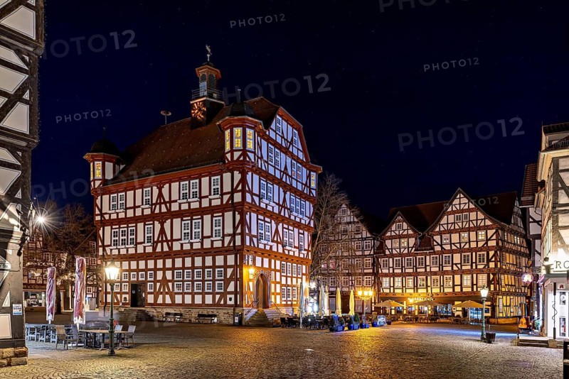 Atmospherically illuminated half-timbered houses in an urban setting at night on a square, The historic town hall of Melsungen