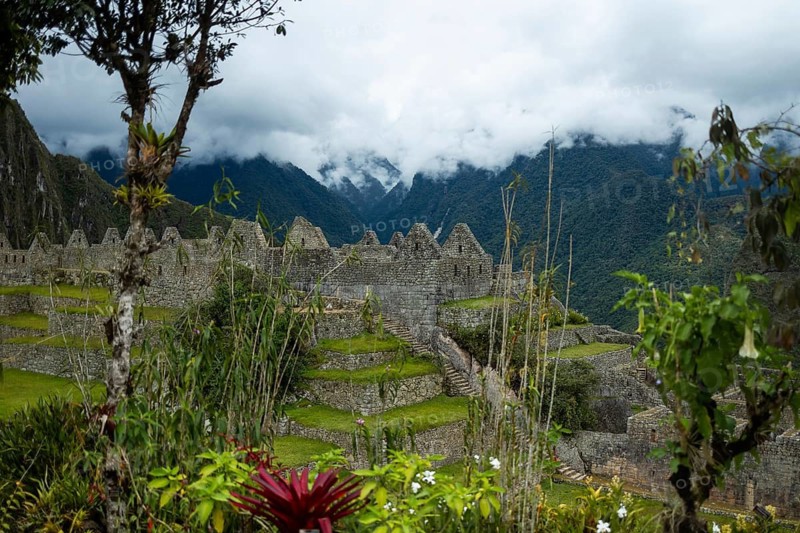 Stunning scene of the ancient Inca site of Machu Picchu, Peru, framed by lush greenery and ethereal cloud-covered mountains