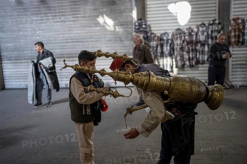 Damascus, Syria. December 5th 2025. A traditional Syrian juice seller serves a young boy in Souk Al Hamediyeh an historical market at the entrance the walled Old City of the Syrian capital, Damascus, Syria