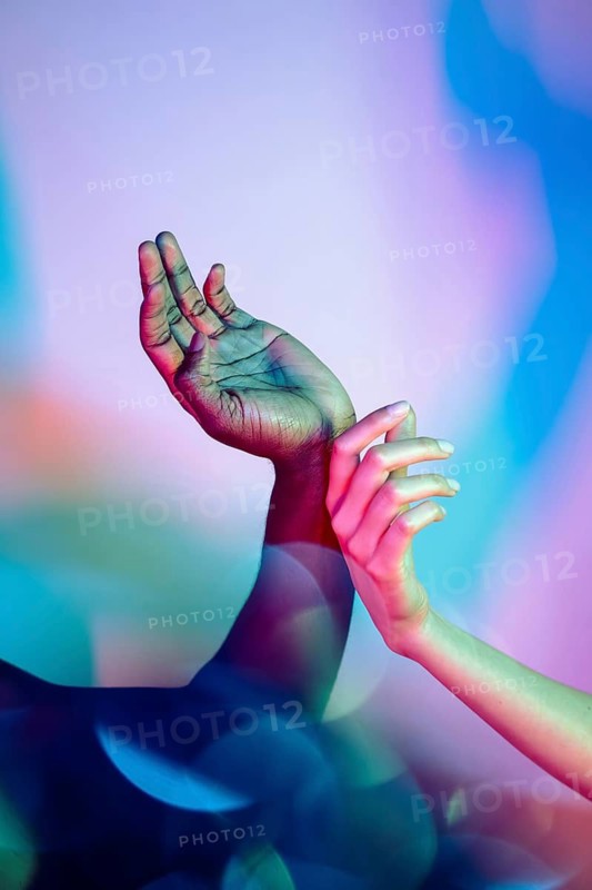 A visually striking image showcases multiethnic hands in an embracing pose, illuminated by vivid gradient colors. This artistic composition symbolizes unity and diversity