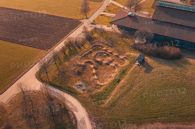 Curvy area of earth seen from above near a building, with surrounding fields and country road, bike park, Gechingen, Calw district, Germany