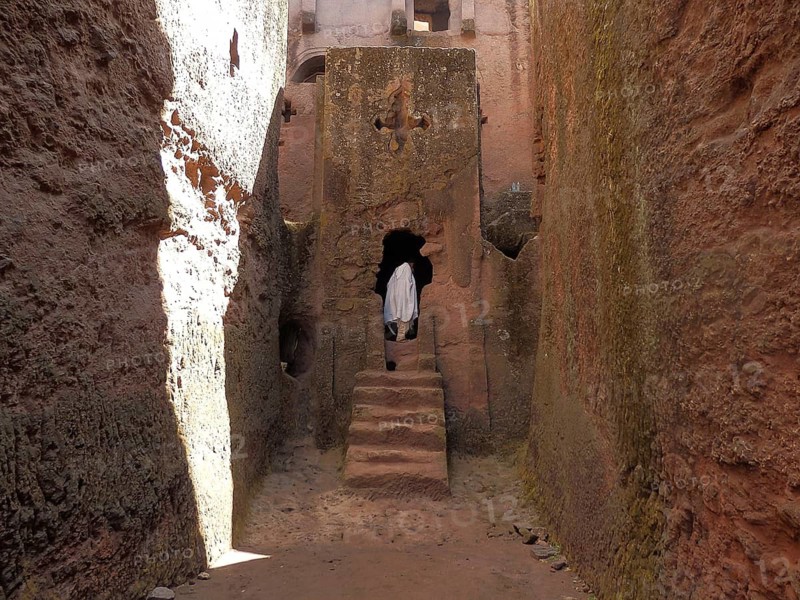 A person dressed in white enters a rock church through a narrow alley, UNESCO World Heritage Site, Lalibela Rock Church, Ethiopia
