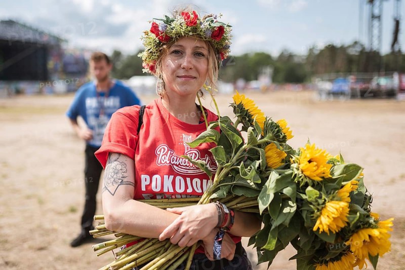 KOSTRZYN NAD ODRA, POLAND - AUGUST 1, 2019: Woman from Peaceful patrol with sunflowers in the entrance to music festival Pol'and'Rock.