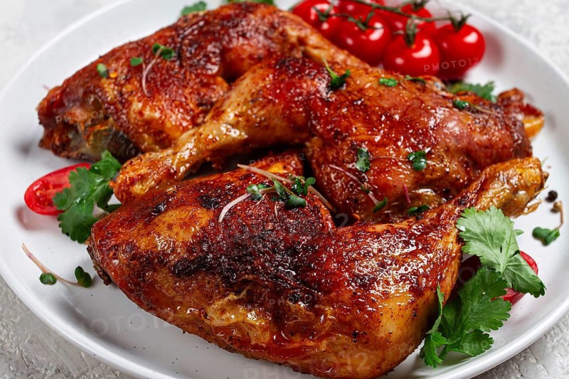 Grilled fried chicken legs, served, with fresh cherry tomatoes, and herbs, on a white plate, homemade, no people