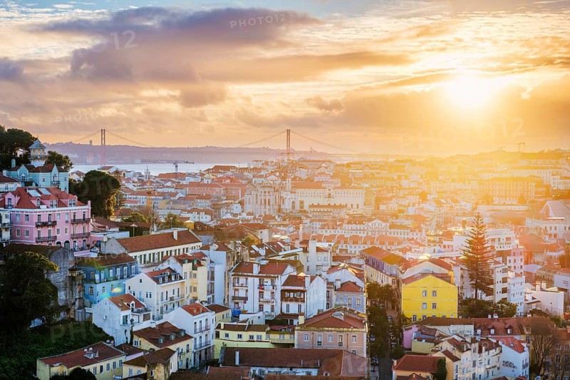 Beautiful view of Lisbon at sunset from Miradouro da Senhora do Monte, showcasing the cityscape and iconic bridges