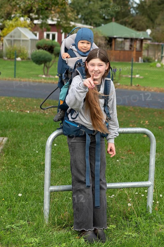 Girl, 10 years old, carrying her little nephew in a back carrier, Mecklenburg-Vorpommern, Germany