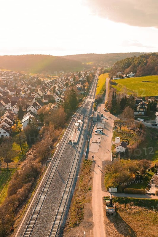 View of a village with railway line and adjacent fields in sunset light, Hermann Hesse Railway, Ostelsheim, Calw district, Germany