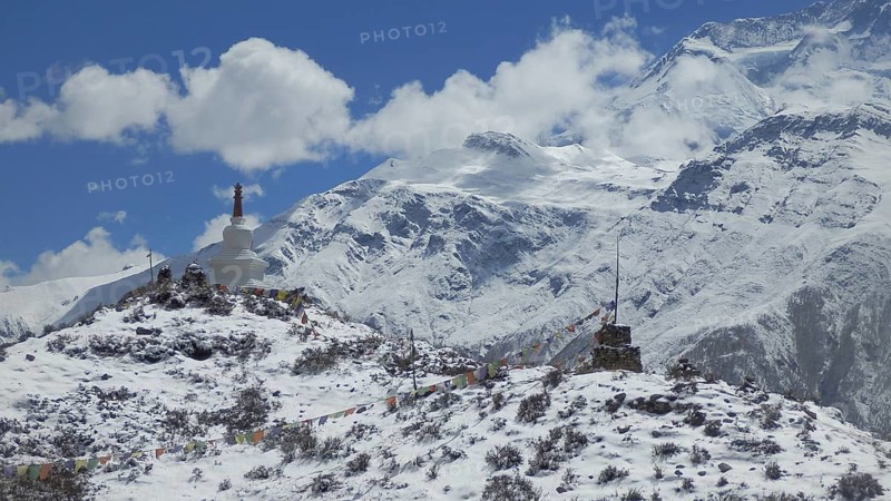 Snowy hill with stupa and prayer flags in the Himalayas, trekking at Annapurna Circuit, Manang, Nepal