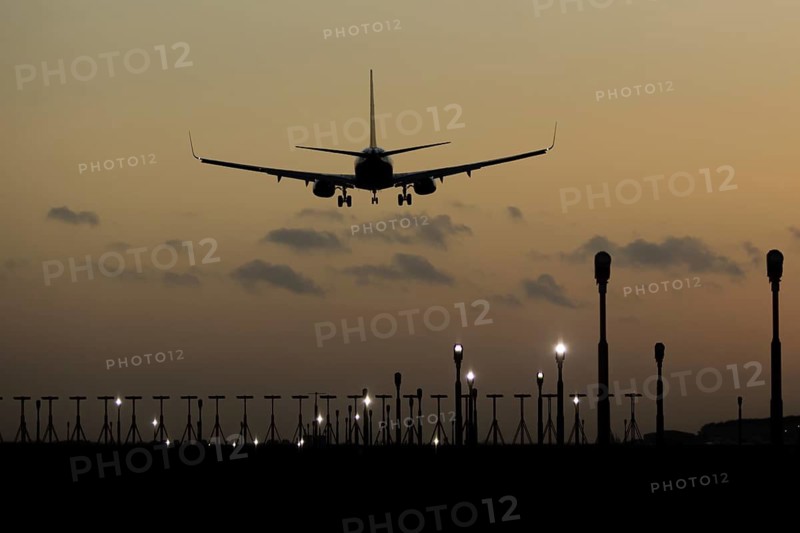 Boeing 737 commercial passenger airliner jet aircraft of Ryanair airways in flight on approach to land over runway lights at sunset at London Stansted airport, Essex, England, United Kingdom