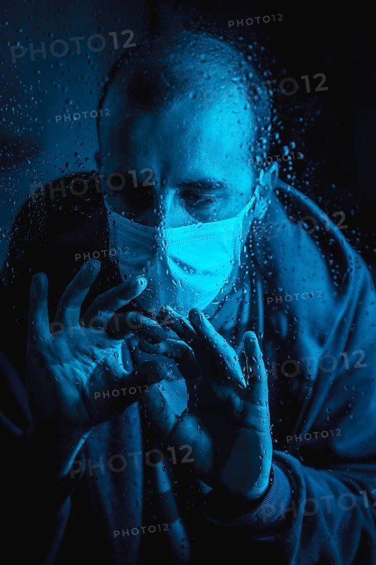 A young man wanting to leave home in the quarantine of the covid 19 one rainy night with a mask