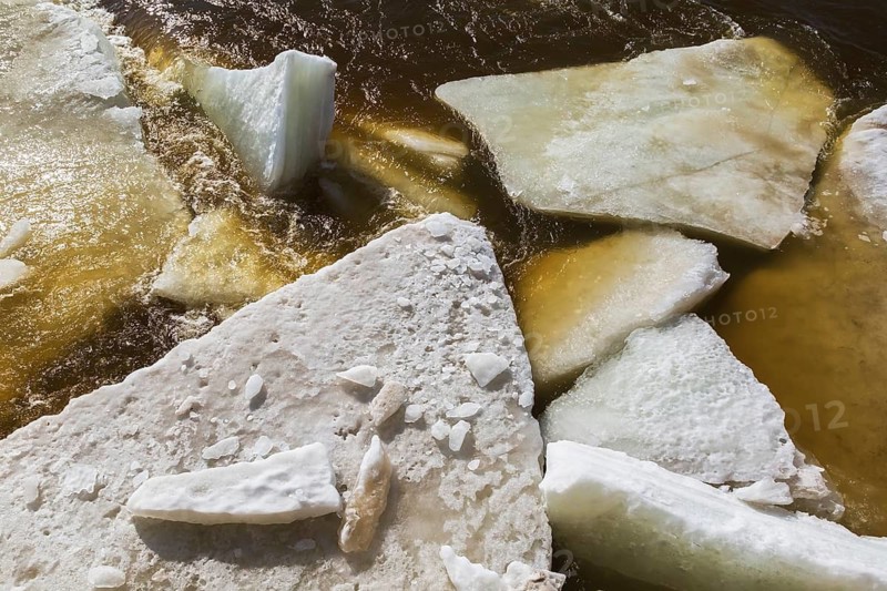 Close-up of large blocks of thick jagged ice floes floating on the surface of the Mille-Iles river during warm weather in late winter, Old Terrebonne, Quebec, Canada