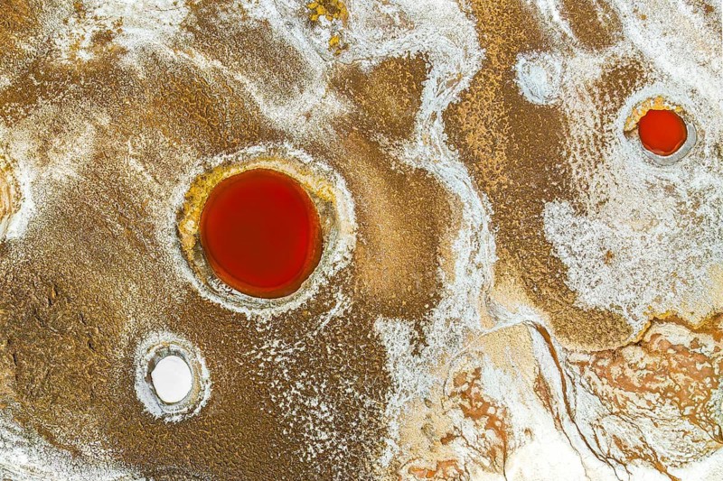 Top view, this drone captured image shows the striking mineral pools of Salar de Antofalla in Catamarca, Argentina. Vivid orange and white mineral deposits create a mesmerizing pattern on the landscape