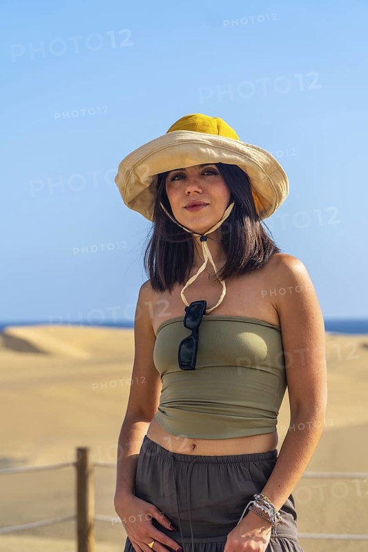 Young woman wearing a sun hat enjoying the sunny landscape of the maspalomas dunes in gran canaria, spain