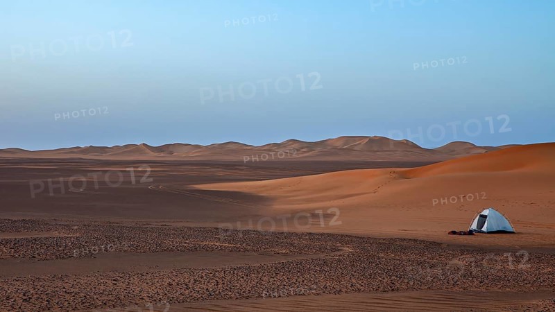 A single tent in a quiet desert at dawn with a wide view, tent camp in the Sahara desert between the sand dunes in Algeria