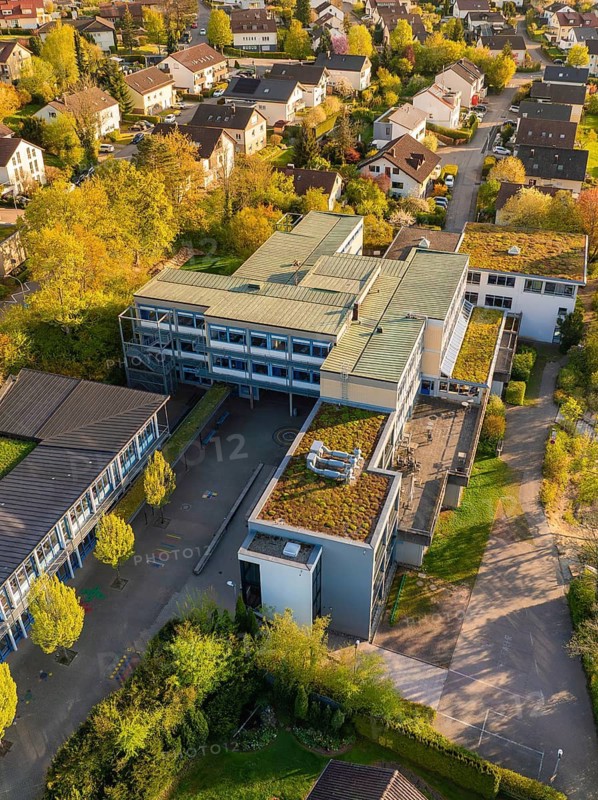 Aerial view of a modern building surrounded by trees in autumnal colours in a residential area, Christiane Herzog Realschule, Nagold, district of Calw, Germany