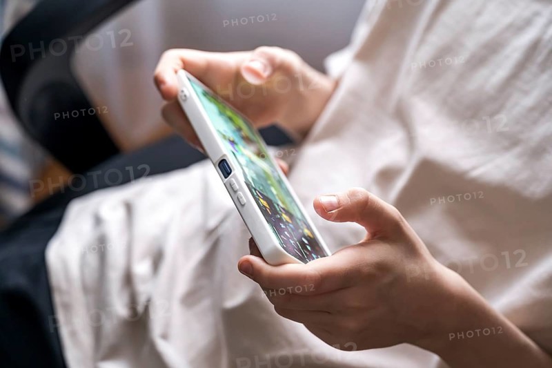Close-up of a teenage boy playing a game on a smartphone. His focus and engagement highlight modern digital entertainment and youth gaming culture