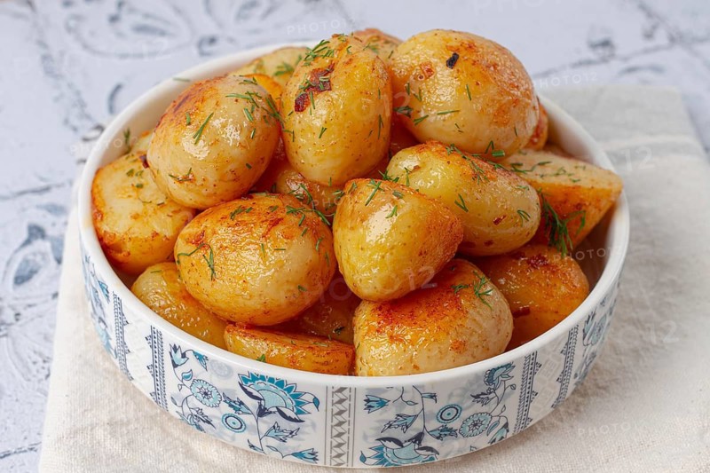 Baked new potatoes, with butter and dill, on a white plate, at home, no people