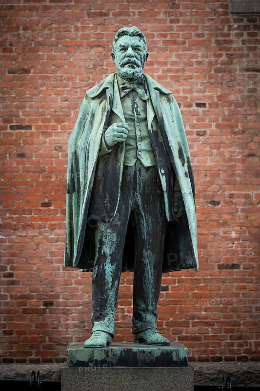 Bronze statue of Carl Jacobsen, Danish brewery entrepreneur, art collector and benefactor, in front of brick wall on plinth, Carlsberg district, Copenhagen, Denmark