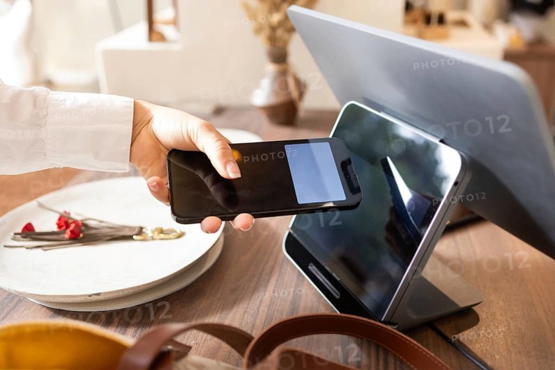 A customer uses a smartphone for a contactless payment at a modern point of sale terminal in a stylish bag store, demonstrating the convenience of digital transactions