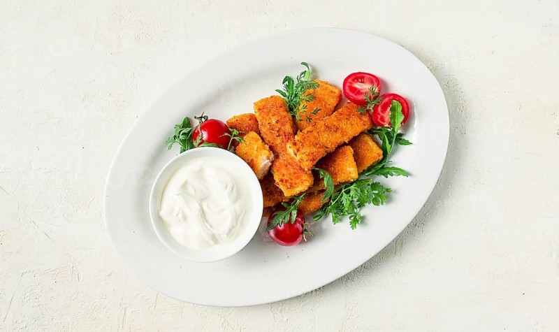 Fried fish nuggets, with white sauce, arugula and cherry, no people