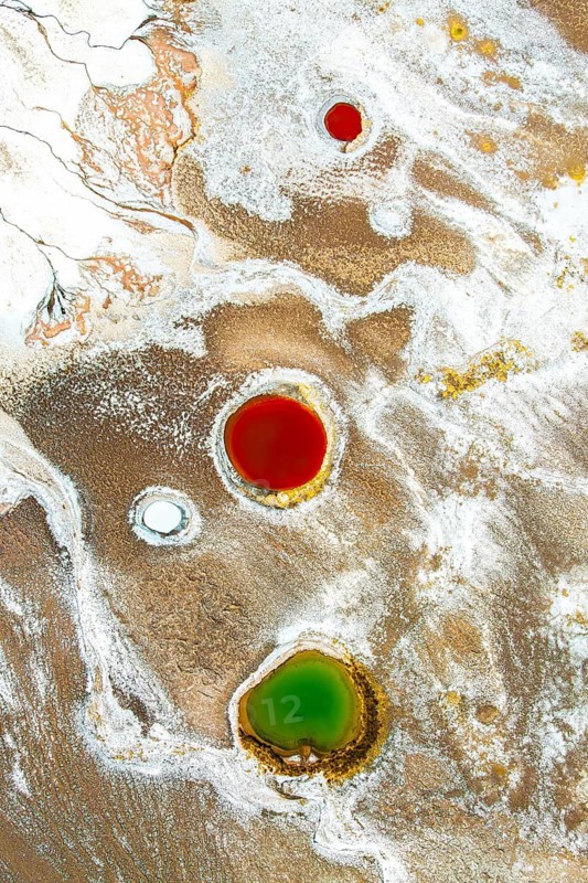 Top view of the colorful salt ponds in Salar de Antofalla, Catamarca, showcasing a contrast of bright red, green, and white against the textured salt flat, captured by a drone in the Andes of Argentina