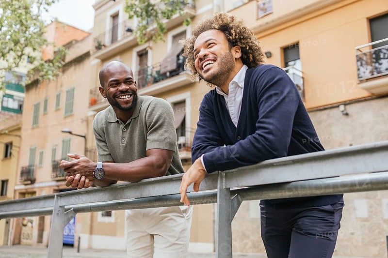 Two colleagues share a light moment outside their office in a charming Barcelona street, showcasing the vibrant and collaborative spirit of modern coworking spaces in the city