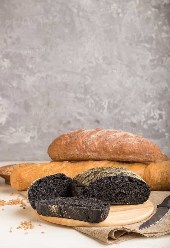 Sliced black bread with different kinds of fresh baked bread on a gray concrete background. side view, close up, selective focus
