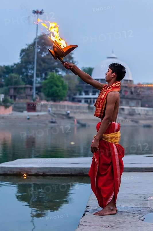 UJJAIN, INDIA, APRIL 23, 2011: Brahmin performing Aarti pooja ceremony on bank of holy river Kshipra. Aarti is Hindu religious ritual of worship, part of puja when light is offered to one or more deities