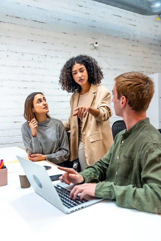 Vertical photo of an hispanic female boss scolding two employees in a coworking space