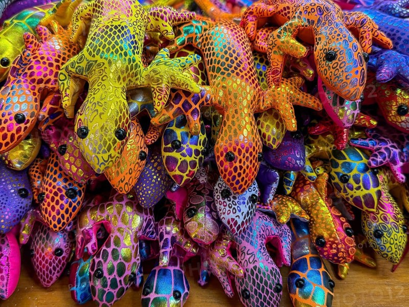 Vibrant, multicolored fabric lizard souvenirs on display at a bustling Thai market. The intricately patterned textiles showcase the rich culture and artistic traditions of Thailand