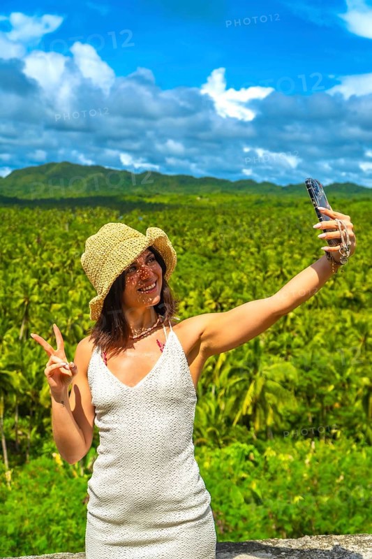 Young woman taking a selfie with victory sign at a coconut plantation in siargao island, philippines