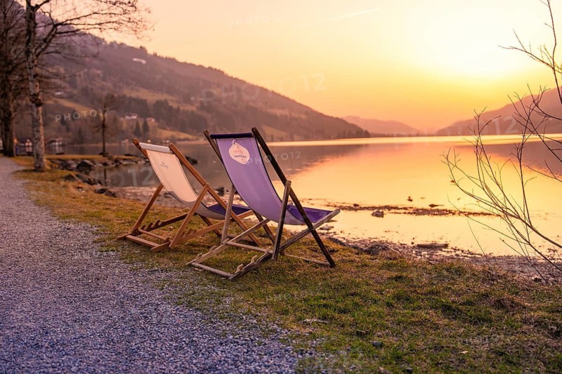 Two deckchairs stand on a gravel path on the lakeside at sunset, Großer Alpsee, Immenstadt im Allgäu, Bavaria, Germany