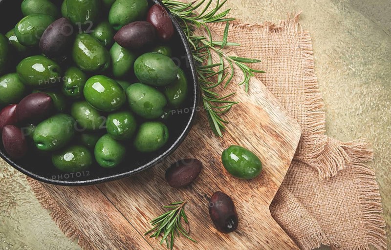 Chalkidiki olives, classic Greek green olives, in a bowl on a cutting board, top view, without people