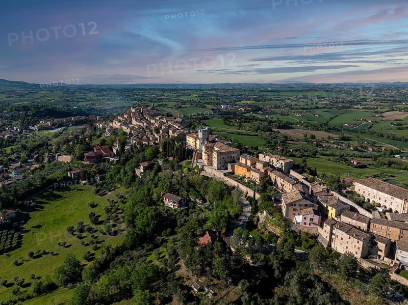 Breathtaking aerial view of Treia, Italy, showcasing historic architecture amid lush greenery and rolling hills under a clear blue sky, capturing the essence of Italian charm